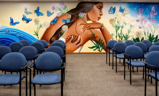 Mural of native American woman with butterflies and blue chairs in front