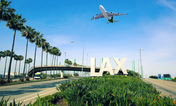 Airplane flying over LAX sign on a sunny day