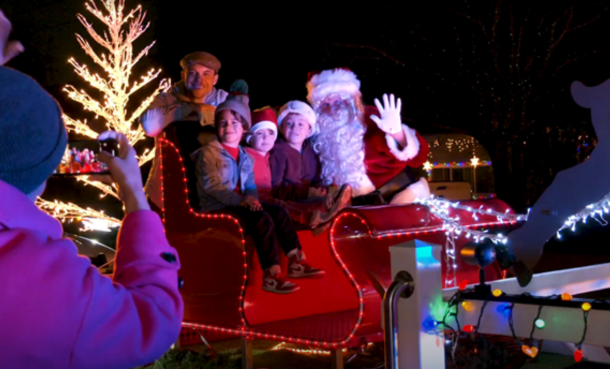 Santa in sleigh with kids smiling and waving