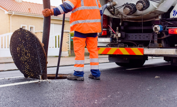 Open sewer manhole with construction worker