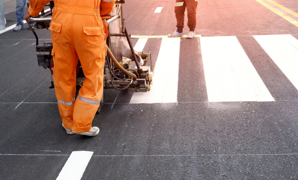 Construction worker striping a crosswalk