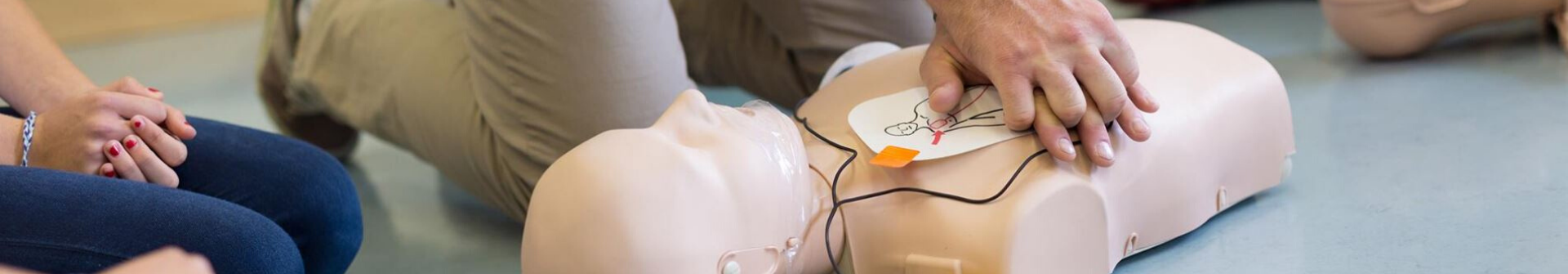 Hands performing chest compression on dummy